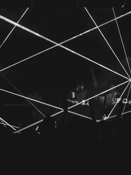 A black and white shot capturing the geometric laser patterns during a set. The light show is as much a part of the performance as the music itself.