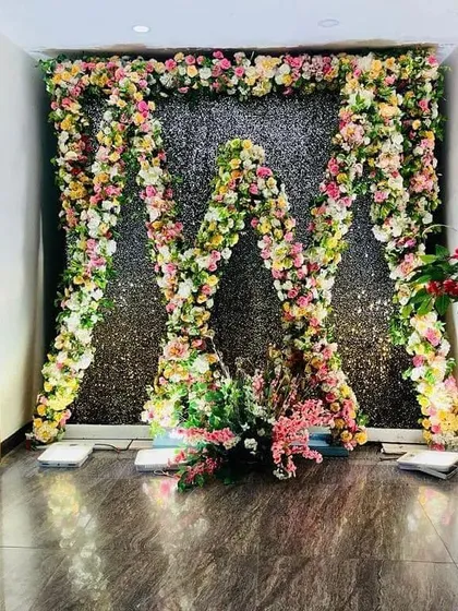 An eye-catching entrance decor featuring a mix of colourful flowers and a sparkling shimmer wall. This design is perfect for adding a touch of glamour to a sangeet or reception party.
