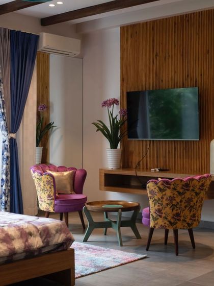 A seating area within the bedroom, featuring ornate purple and yellow chairs that complement the colors in the wall mural, creating a cohesive and artistic space.