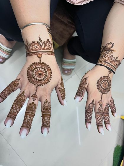 The timeless beauty of a round circle mehndi design, also known as a mandala. It's connected to the fingers with delicate dotted lines, resembling hand jewelry.