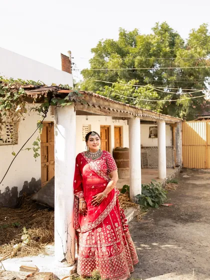 A full-length shot showcasing the grandeur of the red lehenga and how the makeup and styling create a cohesive and regal bridal portrait.