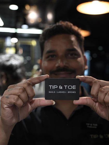Our team is the heart of our brand. A smiling technician proudly presenting the Tip & Toe name.