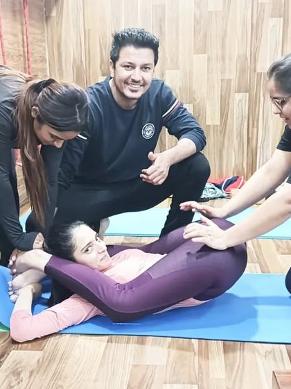 Careful guidance is key. An instructor and fellow students provide support for a deep spinal twist in Yoganidrasana.