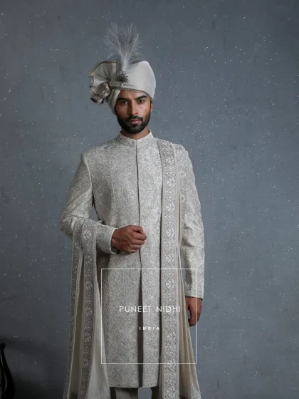 Carved in time, this ivory sherwani is adorned with resham and zari aariwork, floral vines, and zardozi grace. The stole, edged in heritage, completes this masterpiece.