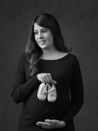 A beautiful solo portrait of the mother-to-be holding a tiny pair of shoes. This black and white image is a sweet and symbolic way to represent the little one on the way.
