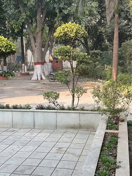 A clean and functional outdoor patio space integrated with surrounding garden beds. We design hardscapes like this paved area alongside topiary trees and flower beds for a complete outdoor solution.
