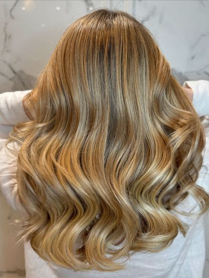This shot captures the full, voluminous look of the pearl blond balayage, styled in beautiful waves.