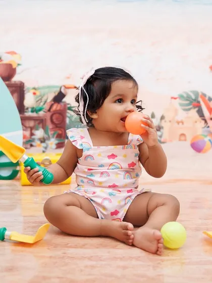 A candid moment of a one-year-old girl playing with beach toys during her themed session.