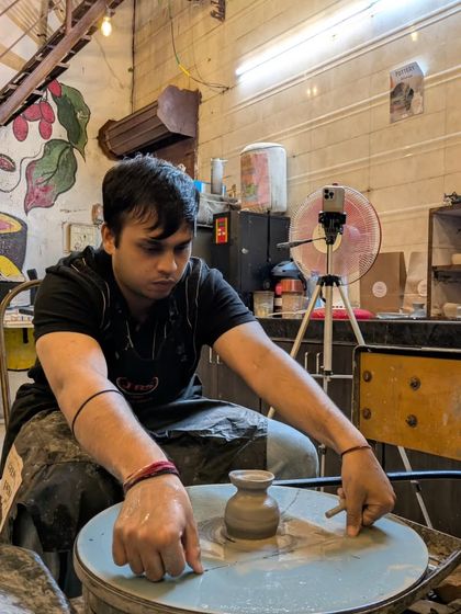 A participant is completely focused as he shapes a small vase on the pottery wheel. You can see the concentration and care that goes into learning this new skill.