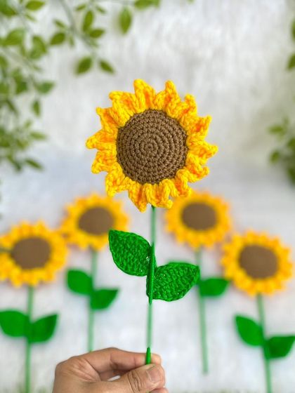 A single crochet sunflower from the bouquet, held up to show its detail. I take great care in crafting each petal and leaf.