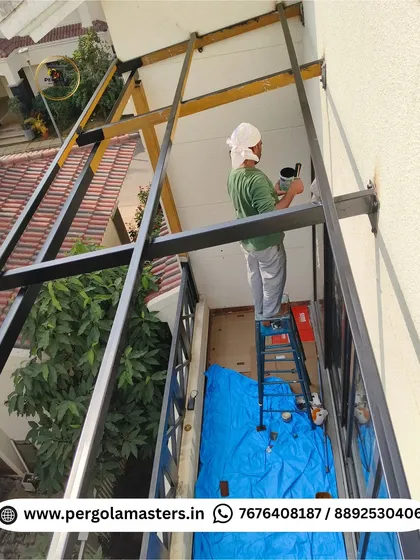 A painter carefully applies a protective coating to the metal frame of a pergola high above the ground. This step is essential for ensuring the structure's longevity and resistance to weather.