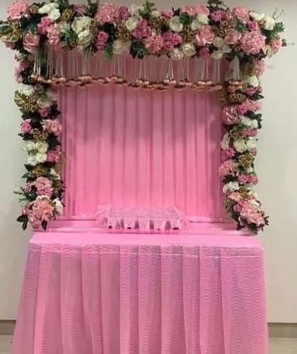 A beautiful all-pink themed mandap decoration. The setup features a full arch of pink and white flowers over a matching pink draped table, creating a soft and devotional ambiance.