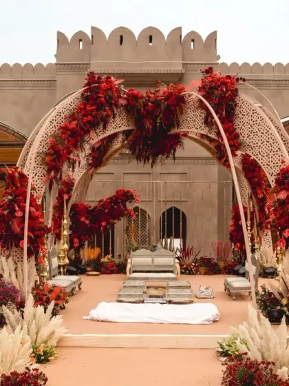 The stunning open-air mandap with its intricate arches and vibrant red floral decor, set against the majestic backdrop of Fairmont Jaipur.