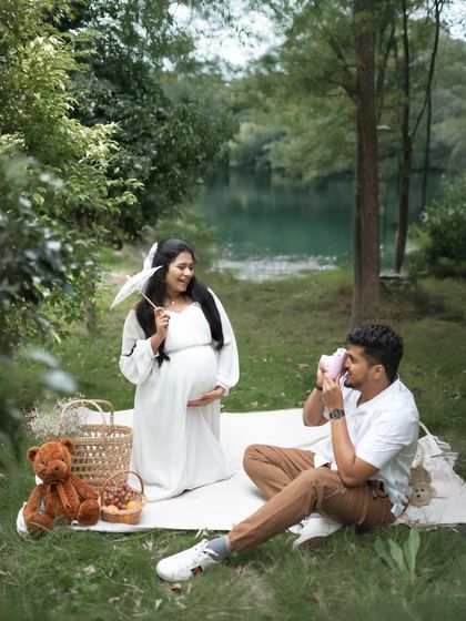 Capturing the fun of the moment. The dad to be takes a photo of his partner during their picnic, a sweet meta moment that tells their story.