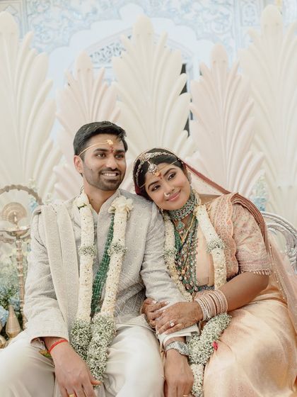 A portrait of the couple, seated at their mandap. The feather-like panels behind them were inspired by the idea of new beginnings and dreams taking flight.