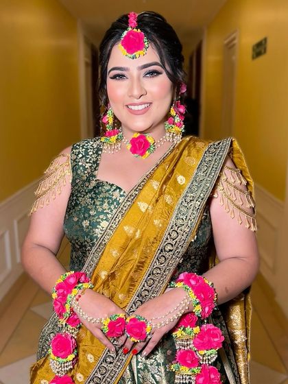 Another shot of the happy bride, adorned with beautiful floral jewelry for her Mehendi.