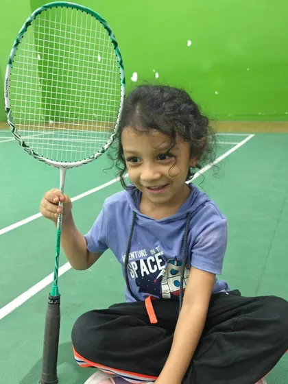 A happy student poses with her racket after a good session. My goal is to build confidence and a genuine passion for badminton in every child.