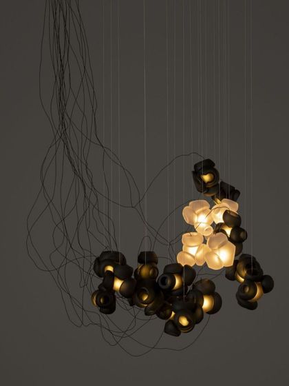 A studio shot of a Bocci 100 series chandelier, showing the chaotic yet beautiful arrangement of the pendants and their tangled cords.