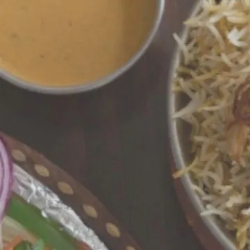 A tempting glimpse of a Mughlai feast, featuring fragrant biryani and a rich, creamy curry. Our chefs specialize in creating royal Mughlai spreads for your special occasions.