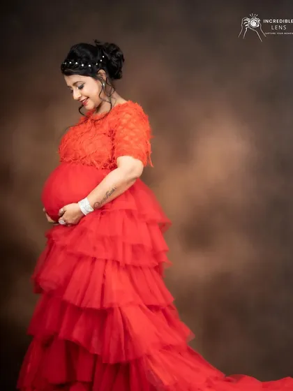 A vibrant look for a maternity shoot in a red ruffled gown. The makeup is fresh and radiant, complementing the bold color of the dress.
