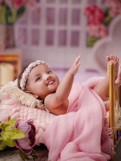 A wave from the princess. This older baby is awake and interactive, enjoying her time in this beautiful pink floral setup.