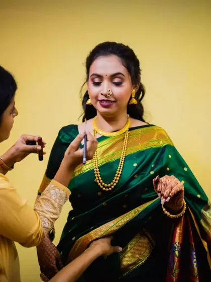 A candid moment of me applying the final touches. The bride is wearing a beautiful green saree, and her makeup is kept soft and glowing for her engagement ceremony.