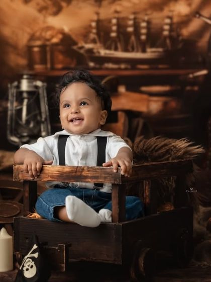 A joyful, upward glance from our little captain in his pirate-themed adventure, surrounded by treasure and nautical props.