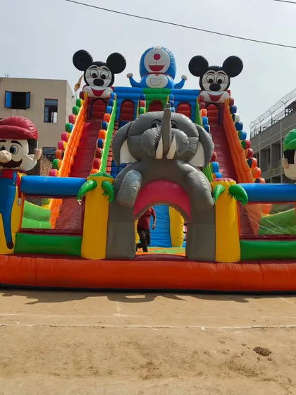 Another angle of the multi-character bounce house, showing the elephant-themed tunnel and the tall dual slides.