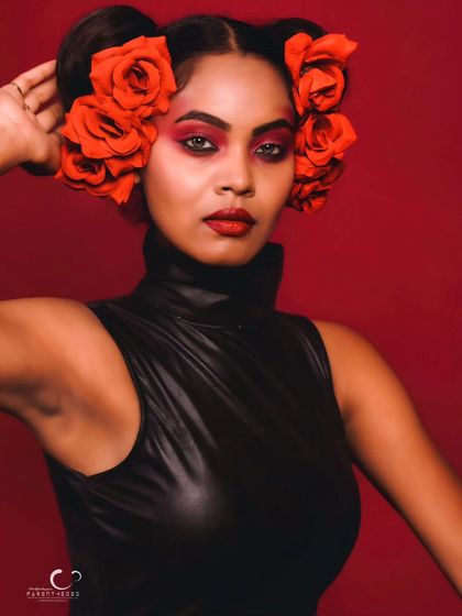 A stunning close-up beauty shot. The red floral hairpiece and matching eye makeup create a cohesive and artistic look that is unforgettable.