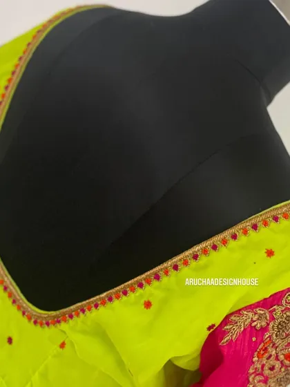 A close-up of the neckline of a neon green blouse, showing the simple yet colorful embroidery detail.