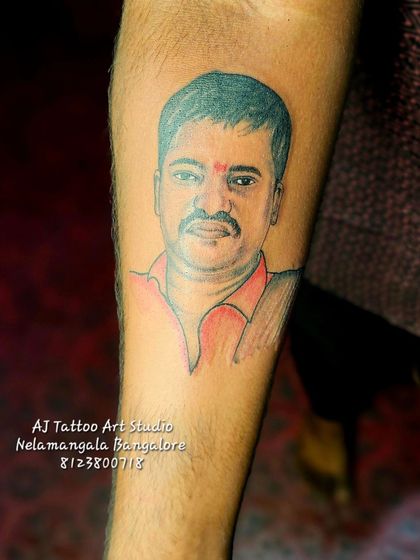 A custom portrait tattoo on the forearm with a touch of color in the shirt, making the design pop.