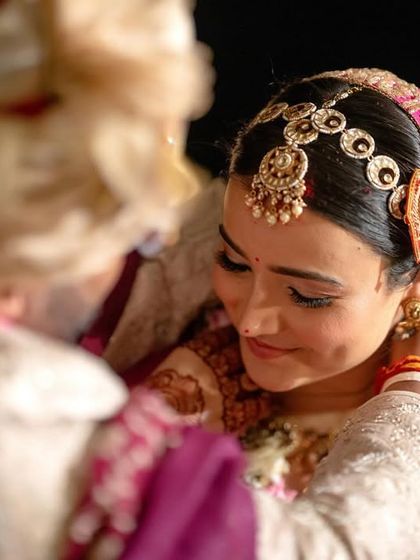 The groom lovingly places the necklace on the bride during the ceremony, a tender and significant moment.