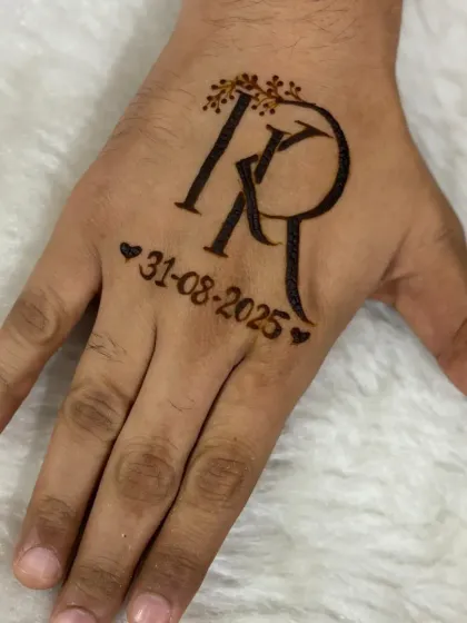 A clear, still shot of the groom's initial monogram. The letters are intertwined and adorned with a delicate leafy vine, with the wedding date marked by small hearts.