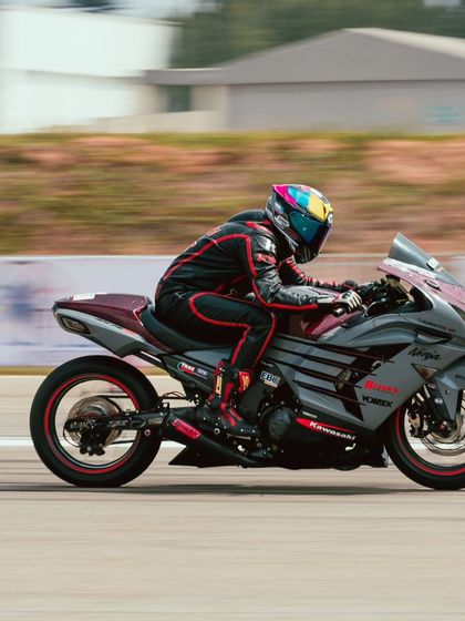 A rider on a grey and red Kawasaki Ninja ZX-14R with a custom paint job, adding a unique flair to the competition.