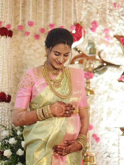 A full-length shot of Savitha at her baby shower. The entire look is one of grace and maternal beauty.