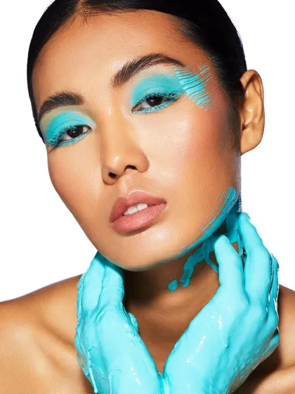 A close-up of the turquoise look, highlighting the texture of the paint and the sharp eye makeup underneath.
