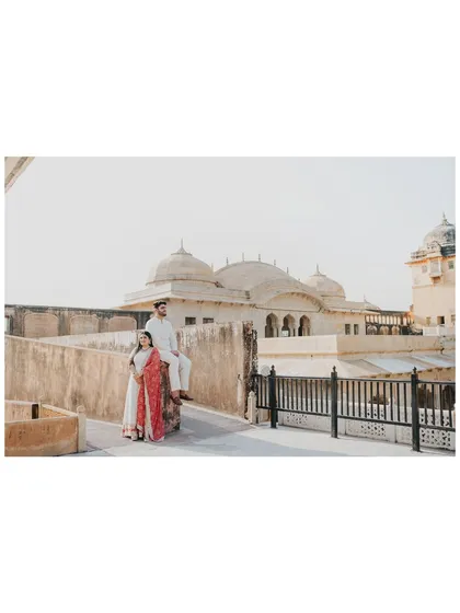 A wide-angle shot capturing the couple against the expansive architecture of Amer Fort, highlighting the grandeur of the location.