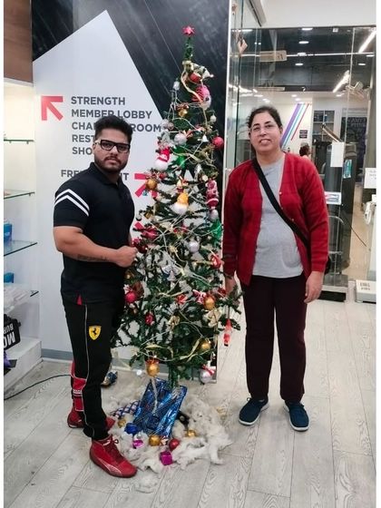 A trainer and member share a moment by our decorated Christmas tree.