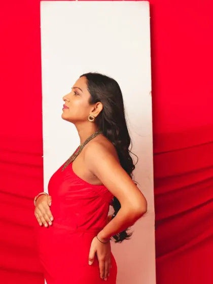 A chic side profile in our red halter-neck gown, highlighting its simple yet stunning design.