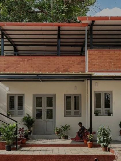 The finished facade of the Anganwadi school, with its clean lines and honest materials like brick and painted plaster. The external staircase and rooftop terrace are not just functional but are designed to be engaging spaces for children to explore.