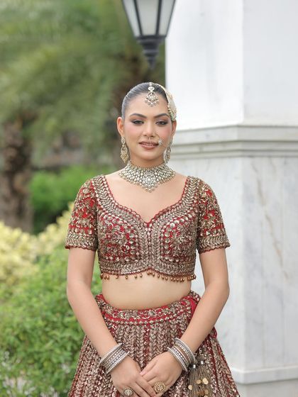 A classic portrait of the bride in her red lehenga. The detailed work on the blouse and the simple, elegant jewelry make for a timeless photo.