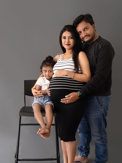 A lovely family portrait with their daughter seated on a chair, creating a fun and engaging composition.
