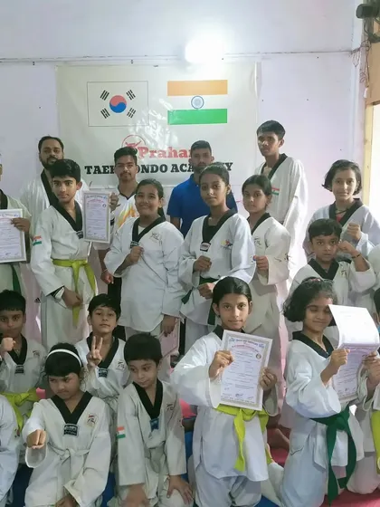 A group of our students, from yellow to green belts, proudly holding their promotion certificates.