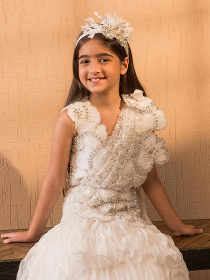 This handcrafted white lehenga is adorned with delicate floral appliqués and pearl embellishments for a soft, romantic look.