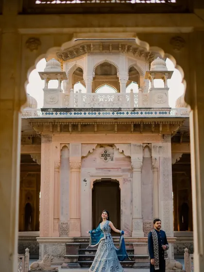 Using the palace arches to create a natural frame, this shot captures the bride in a moment of elegance. It showcases her beautiful lehenga and the stunning architectural details of the location.