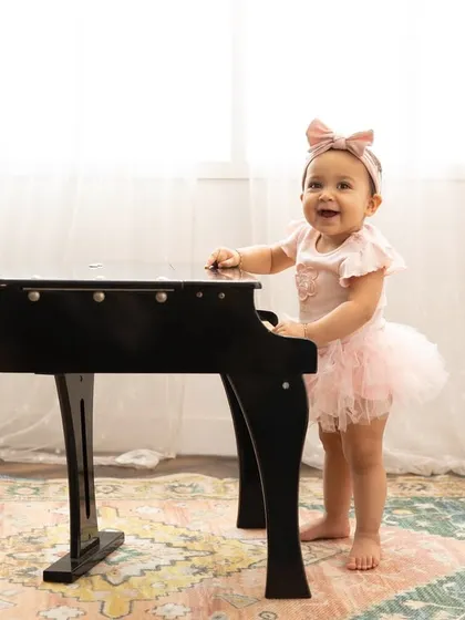 A tiny pianist making her debut. Themed shoots with props like this miniature piano add a touch of charm and personality to your baby's portraits.