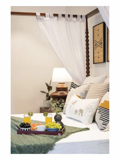 A close-up of the master bedroom, where a breakfast tray sits on the bed. The mood board for this holiday home included themes of sun and waves, which we translated into a palette of blues, yellows, and greens, and soft, natural textiles.