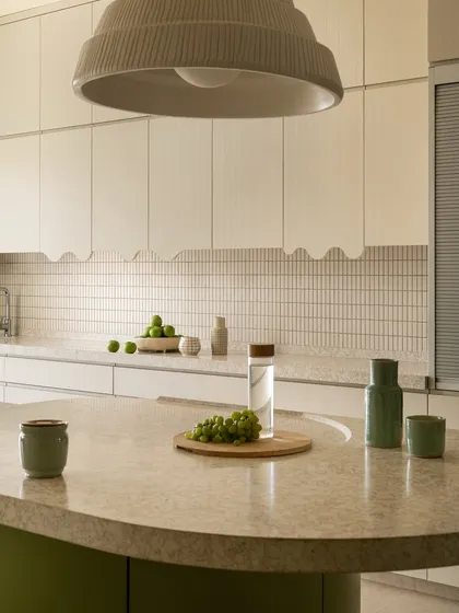 This spacious and fun kitchen was designed around the circular layout of the living room. It features a curved green island that serves as both a cooking and breakfast area, with a large dome light overhead.