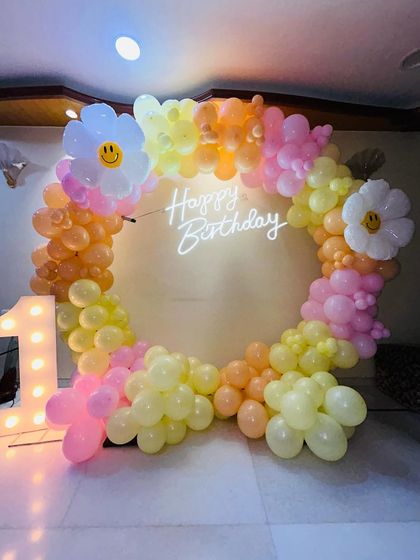 A different angle of the pastel daisy-themed first birthday, showing the full circular shape of the balloon arch.