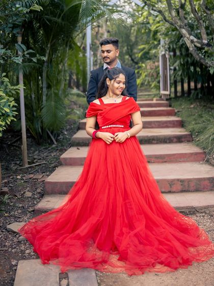 A sweet couple's portrait in a garden setting. The vibrant red of the gown makes the bride-to-be the center of attention.